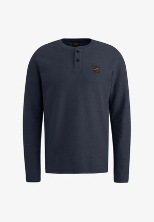 Námornícka košeľa s dlhými rukávmi vyrobená z textúrovaného materiálu. Má okrúhly výstrih s dvoma gombíkmi a malou nášivkou loga na hornej ľavej strane.