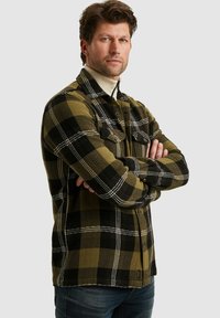 Groen en zwart geruite flanellen shirt met twee borstzakken, knoopsluiting en visgraatpatroon; gestructureerde stof.