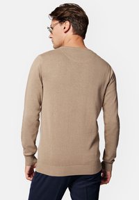 Beżowy sweter dziany z okrągłym dekoltem, długimi rękawami, prążkowanym wykończeniem i gładką teksturą, pokazany z tyłu.