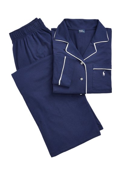 Pijamale din bumbac de culoare bleumarin cu dungi albe. Top scurt cu mânecă, cu nasturi și buzunar, împreună cu pantaloni asortați cu talie elastică. Textură moale a materialului.