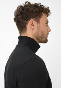Zwarte coltrui met een slim fit ontwerp, een gladde textuur en een hoge kraag. Het materiaal lijkt zacht en rekbaar, geschikt voor het dragen in lagen.