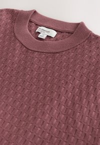 Pull en maille texturée mauve avec un col rond côtelé et une étiquette de taille indiquant "N. Premium Collection M Made in Myanmar."