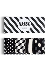 Coffret de chaussettes noir et blanc comprenant quatre paires avec des motifs à pois, géométriques et rayés en tissu doux, présenté dans une boîte thématique.