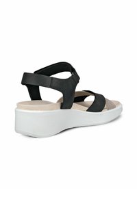 Musta sandaalit, joissa on korkea korko, ja joissa on teksturoitu hihna, sileä takapinta ja kontrastivärinen beige pohja. Säädettävä nilkkahihna mukautettavuutta varten.