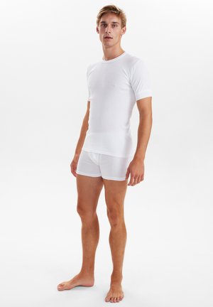 Hvid t-shirt med korte ærmer lavet af blødt materiale, parret med hvide boxershorts, begge med et enkelt design og glat tekstur.