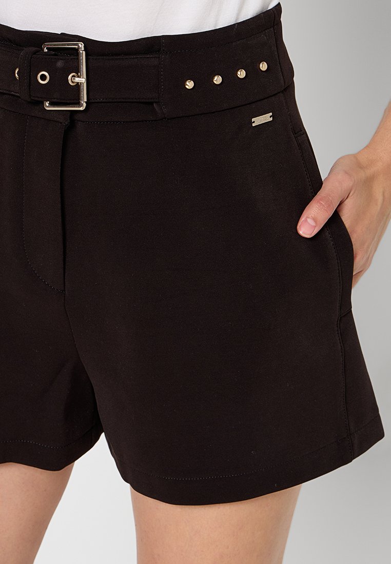 Czarne spodenki z miękkiego materiału, z szerokim paskiem, metalowymi ćwiekami wzdłuż talii i małym srebrnym logo z boku.