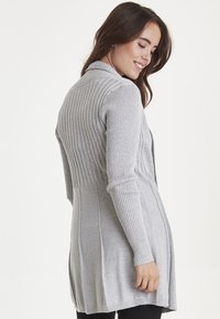 Cardigan grigio con texture a costine, maniche lunghe e design aperto. Presenta dettagli delle cuciture sottili e una vestibilità comoda.
