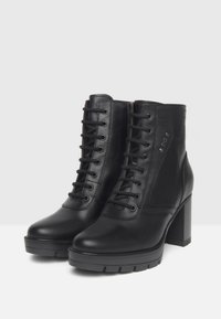 Bottines en cuir noir à lacets avec des talons épais et des semelles crantées, dotées d'œillets en métal et d'un discret logo sur le côté.