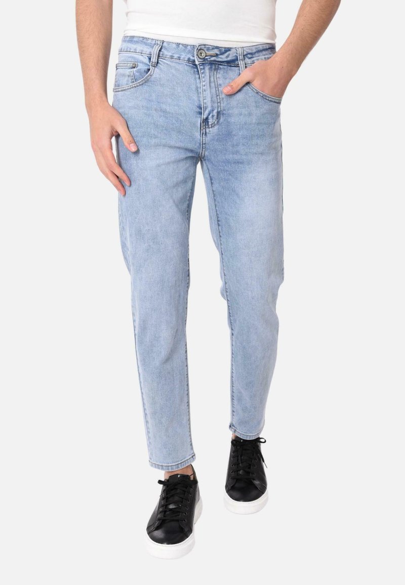 Jeans in denim azzurro chiaro con una vestibilità dritta, design a cinque tasche e chiusura con bottone. Abbinati a sneakers nere con suole bianche.