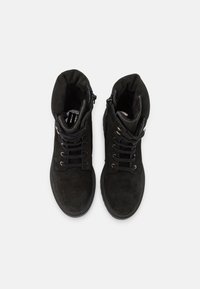 Botas de tornozelo de camurça preta com atacadores, bico redondo e um colarinho macio e acolchoado. Apresenta fecho com zíper e sola de borracha lisa.