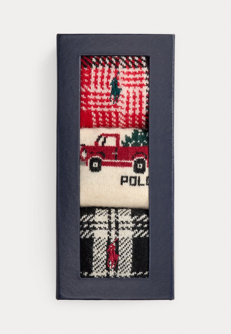 Tres pares de calcetines estampados en una caja de regalo. Diseños en rojo, crema y negro con motivos festivos, incluyendo un camión y patrones de pata de gallo.