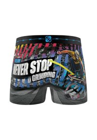 Un caleçon avec un design graphique vibrant représentant un skateur. Les couleurs incluent le noir, le bleu, le jaune et le rouge. Un texte en gras indique "NE JAMAIS S'ARRÊTER DE TRAVAILLER."