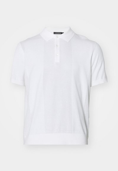 Vit kortärmad polo t-shirt gjord av texturerad stickad tyg, med krage, knappslå och paneldetaljer.