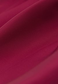 Bordeauxkleurige stof met een gladde textuur, gekenmerkt door een subtiel ribbelpatroon. Het materiaal lijkt lichtgewicht en valt soepel.