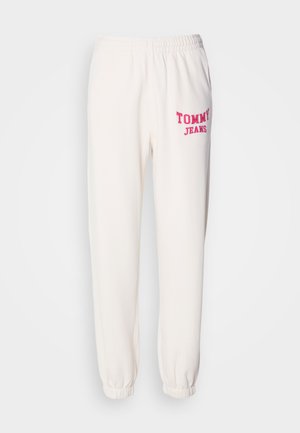 Valged dressipüksid pehmest kangast, kummipaelaga vööl, vasakul küljel roosa "TOMMY JEANS" logo ja ehkatud pahkluude juures.