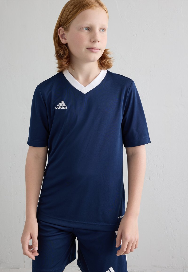 Marinblå Adidas sportsjersey med hvit v-hals, korte ermer og dry-fit stoff. Kombinert med matchende marineblå shorts.
