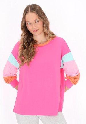 Camicia a maniche lunghe di un vivace colore rosa con maniche colorate in blu pastello, rosa chiaro e arancione. Il tessuto appare morbido e leggermente elasticizzato.