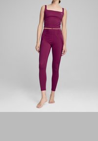 Bordowy sportowy crop top i legginsy wykonane z elastycznego materiału, charakteryzujące się dopasowanym krojem i minimalną ilością szwów dla komfortu i swobody ruchów.