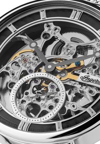 Orologio meccanico argento con quadrante trasparente, che mette in mostra ingranaggi intricati, dettagli neri, un sottodial circolare e decorazioni dorate.