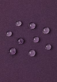 Gouttes d'eau sur une surface en tissu texturé violet, mettant en avant les propriétés imperméables du matériau et le subtil contraste de couleur.