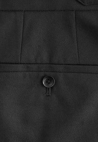 Schwarzer Stoff mit glatter Textur, der einen einzelnen schwarzen Knopf und Nähte entlang der Kanten aufweist, präsentiert ein Taschendesign.