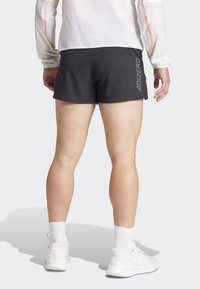 Zwarte sportshorts met een elastische tailleband, met "ADIZERO" -branding aan de zijkant. Gemaakt in combinatie met witte sneakers en crew-length sokken.
