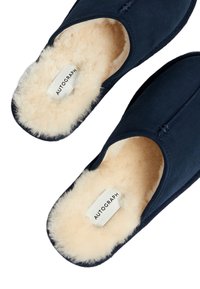 Pantofole blu navy con un morbido rivestimento in shearling color crema, dotate di un'apertura arrotondata e di un'etichetta con la scritta "AUTOGRAPH."