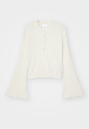 Ribbad, krämfärgad polo skjorta med långa, vida ärmar och femknappsknäppning. Har en krage med mjuk textur.