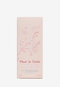 Helles rosa Pappschachtel mit floralen Illustrationen, mit silbernem Text für "L'Occitane" und "Eau de Toilette," 75 ml. Dekoratives und einfaches Design.