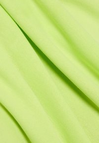 Lichtgroene rekstof met een gladde textuur, met gelaagde plooien en een iets gestructureerd oppervlaktepatroon.