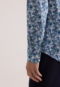 Camicia bianca con motivo paisley blu e verde. Vestibilità slim, polsini con bottoni e colletto appuntito. Tessuto di cotone liscio, design su misura.
