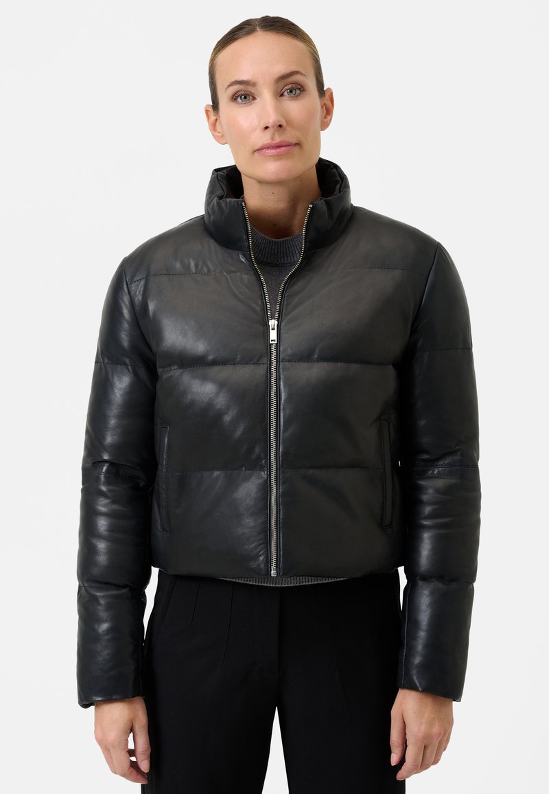 Sort læder cropped pufferjakke med ståkrave, lynlås-lukning og plysset quiltet design. Har en glat overflade og elastiske manchetter.