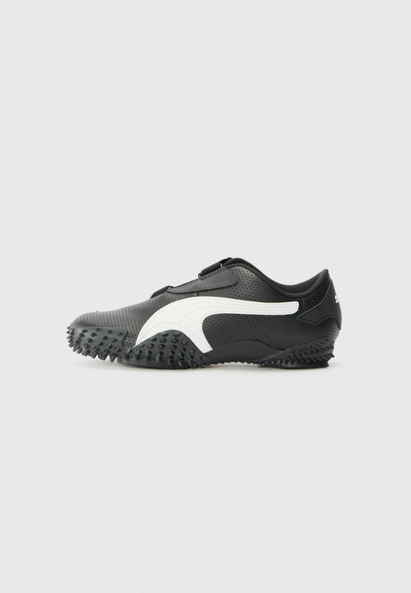 Shoe desportivo preto com um upper texturizado, detalhe em logo branco e sola de borracha com cravos para tração. Bico arredondado e design de baixo perfil.