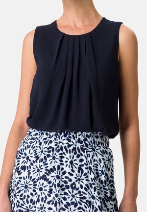 Sleeveless navy top with pleats paired with high-waist skirt featuring blue and white abstract floral pattern.