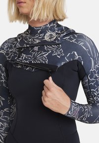 Black wetsuit with floral-patterned sleeves and neck. Features zippers and a logo badge. Smooth texture, long sleeves, tailored fit.