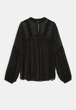Blouse noire transparente à manches longues avec texture à pois, taille froncée, bordure en dentelle et fermeture par lien au niveau de l'encolure.