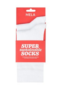 Witte duurzame sokken verpakt in een felrode kaart, gelabeld als "SUPER duurzame SOKKEN." Gemaakt van Fairtrade-katoen, polyamide, vrij van polyester.