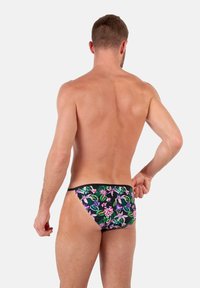Schwarze Schwimmshorts mit einem bunten Blumenmuster in Lila und Pink sowie grünen Blättern. Glatte Textur und enganliegende Passform.