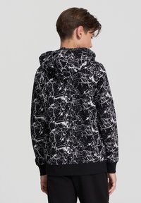 Felpa nera con motivo marmorea bianco, cappuccio e polsini a coste. Texture morbida, vestibilità rilassata e logo discreto sull'orlo.