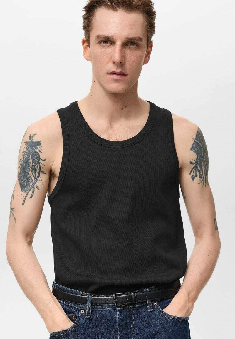 Zwarte katoenen tanktop met ribbeltextuur, brede armsgaten en een ronde halslijn, gedragen met vintage blauwe spijkerbroeken en een zwarte riem.