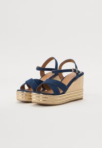 Marinblå kile-sandaler med kryssdesign, jutebelagt plattform og spenneaccent. Glatt tekstur og åpen tå funksjon.