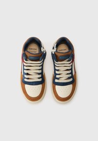 Baskets marron, bleu marine et crème avec un design à lacets, matériaux en suede et cuir, perforations distinctes sur le bout, et une marque sur la languette.