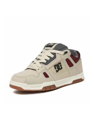 Beżowo-bordowe buty skate DC z białymi sznurowadłami, wyściełanym szarym językiem i brązową gumową podeszwą, widziane z przodu z prawej strony.