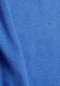 Gros plan sur un tissu bleu lisse, étroitement tricoté, avec des coutures fines et uniformes et de légers plis créant une texture douce.
