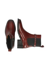 Botas de tobillo de cuero marrón con un panel lateral, tachuelas decorativas y un tacón apilado. Textura suave con acentos de tela elástica.