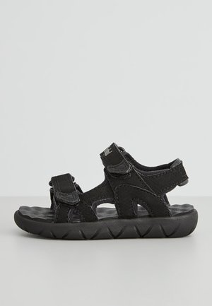 Sort åben sandal med justerbare stropper, tekstureret sål og polstret fodseng, designet til komfort og afslappet brug.