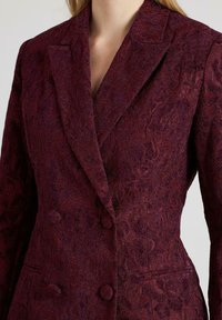 Bordeaux jacquard blazer met bloemtextuur, dubbelzijdig ontwerp, geknipte revers en zijzakken. Professionele pasvorm met gestructureerde schouders.