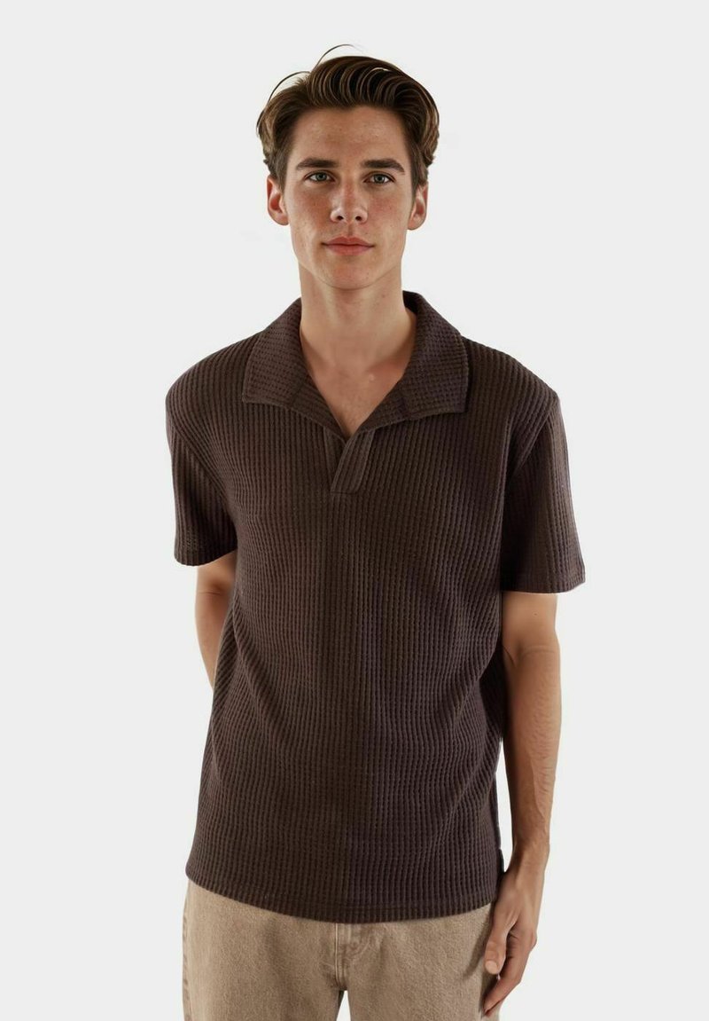 Brun, kortärmad polo med en texturerad, ribbad design och klassisk krage. Smal passform med en subtil, avslappnad look.