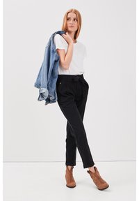 Svarta högmidjade byxor med bälte och uppvikta cuffs, ihopparade med en vit t-shirt och en denimjacka. Bruna ankle boots ger en detalj.