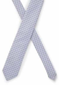 Cravate violette claire avec un motif circulaire en bleu et blanc, fabriquée en tissu lisse, avec une pointe et un design effilé.